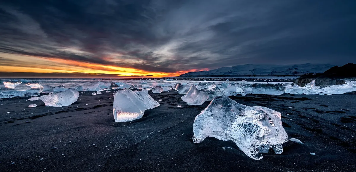 Glacial ice on the black sand of Diamond Beach at sunset