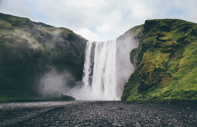 Skógafoss waterfall between green cliffs