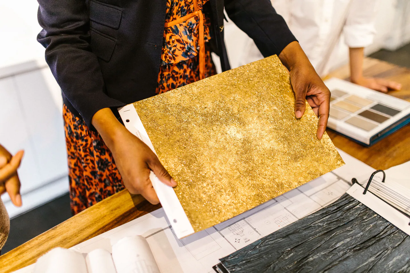 Colleagues comparing material samples and plans around a shared worktable.